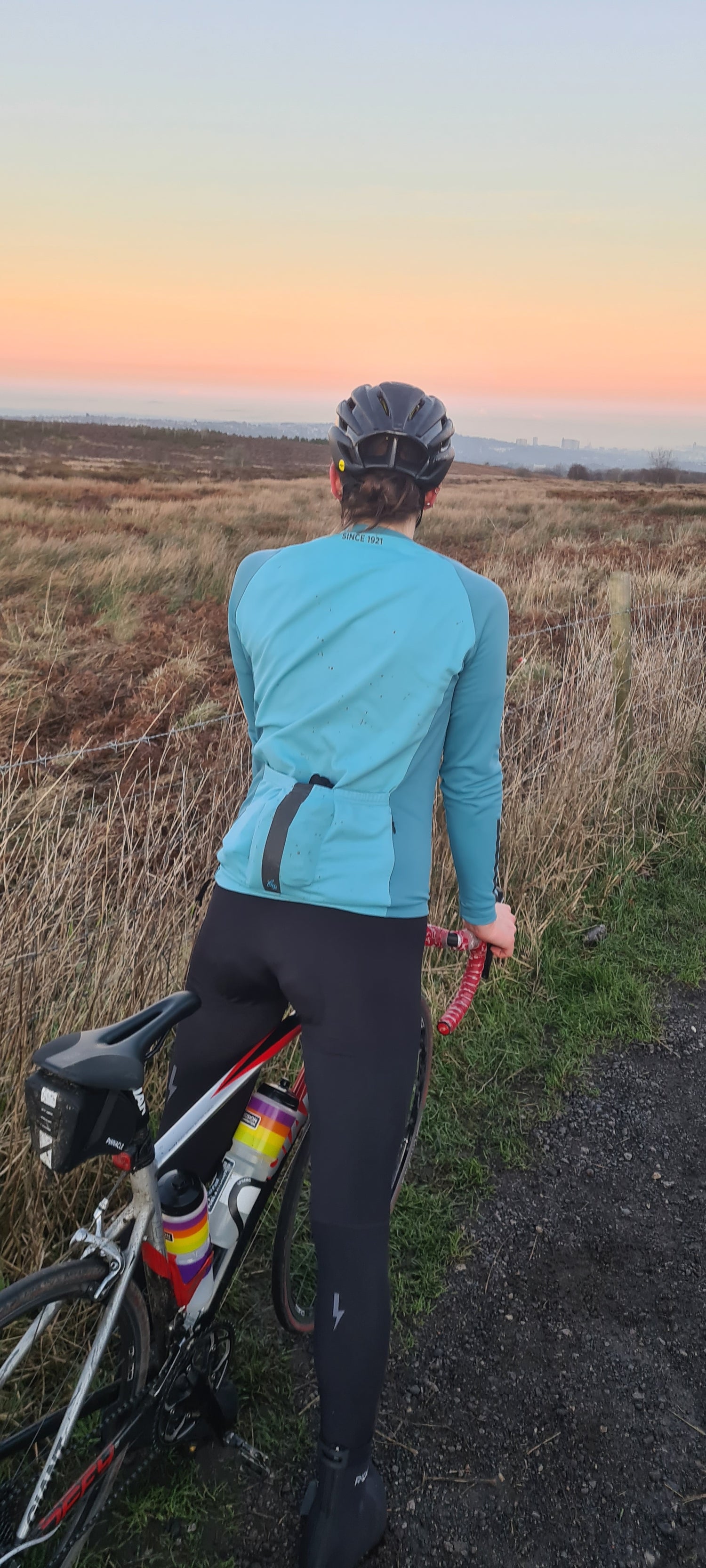 Close-up-back-view-of-a-woman- cyclist-wearing-a-athletic-crop-top-and-black-cycling-leggings-with-a-bold-white-side-stripe