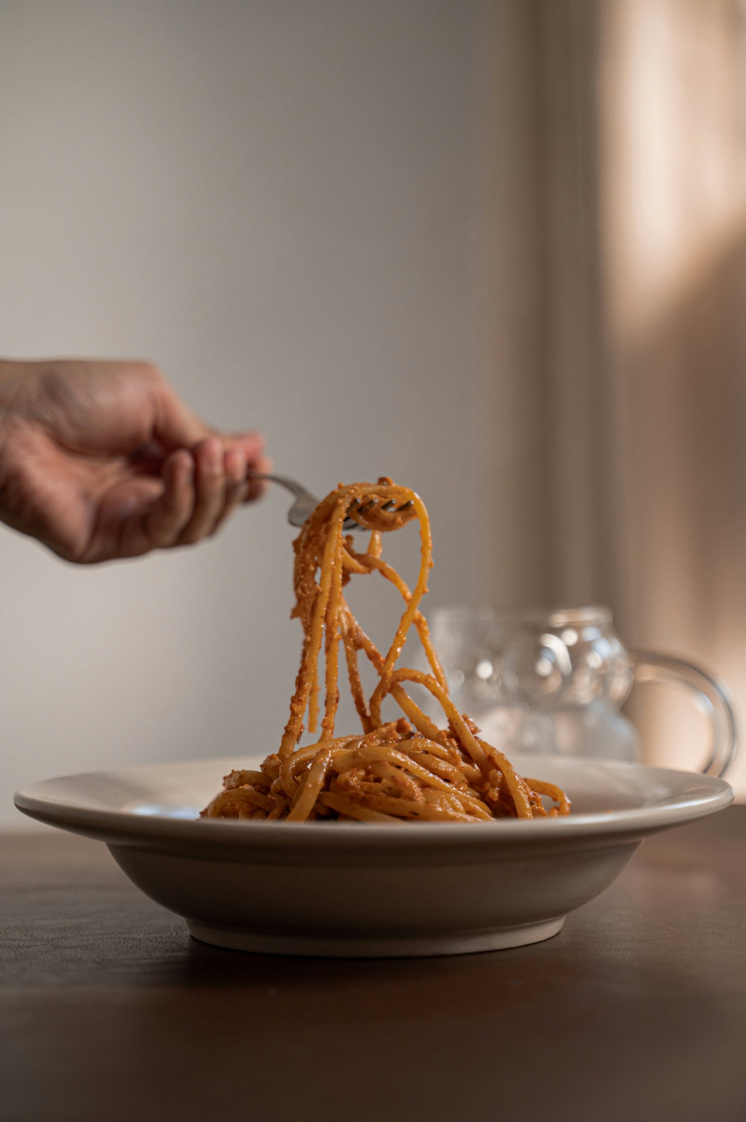 Delicious-homemade-pasta-with- creamy-tomato-sauce-fork-lifting- noodles-from-a-ceramic-bowl