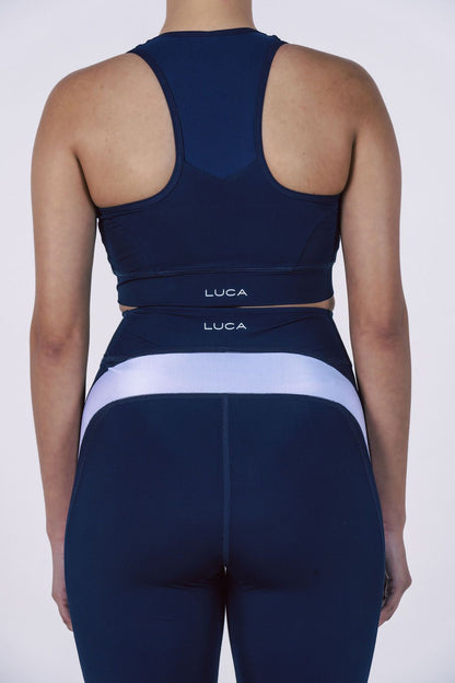 Rear-view-of-a-navy-blue-athletic- set-showing-a-racerback-sports-bra-and-compression-shorts-with-a- wide-horizontal-white-contrast-stripe-and-LUCA-branding