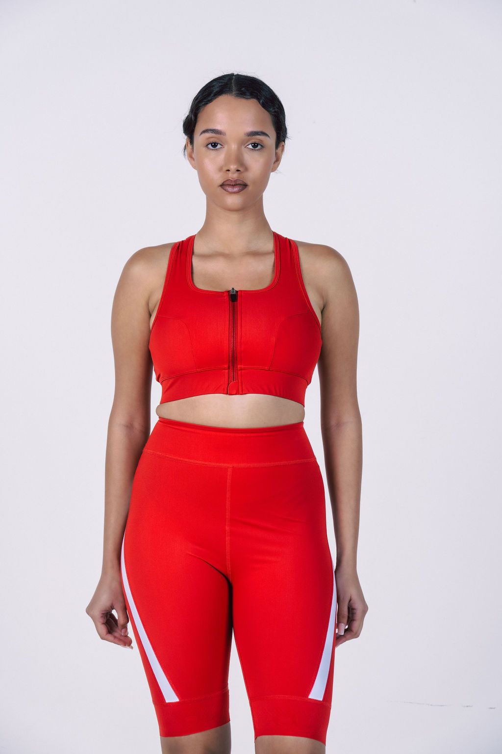 Woman-wearing-bright-red-athletic- outfit-including-a-zip-front-sports-bra- and-high-waisted-biker-shorts-with- white-stripe-accents-on-the-leg-Ideal- for-cycling