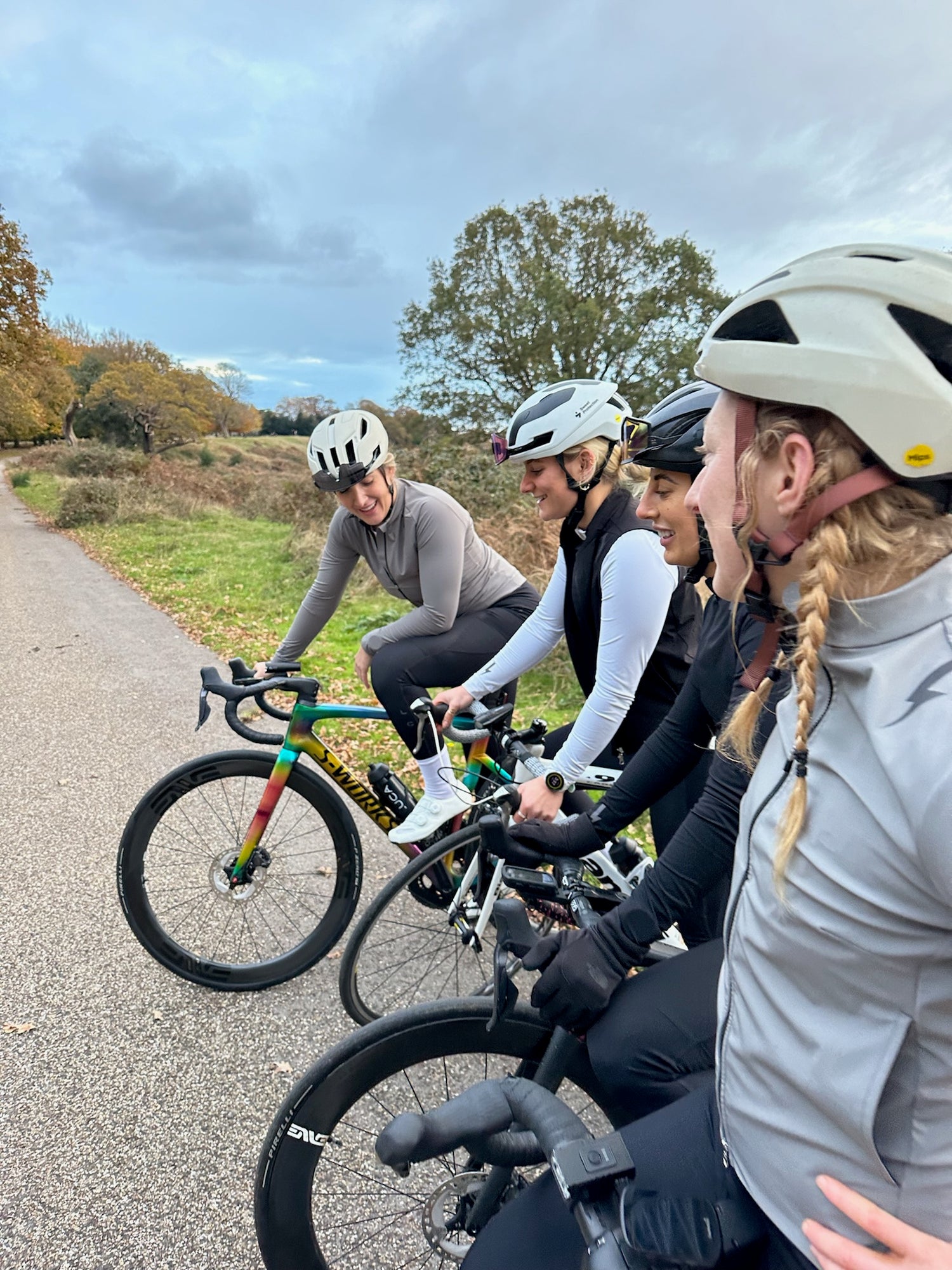 Group-of-four-women-cyclists-riding-road-bikes-together-on-an- autumn-path-in-a-park-area