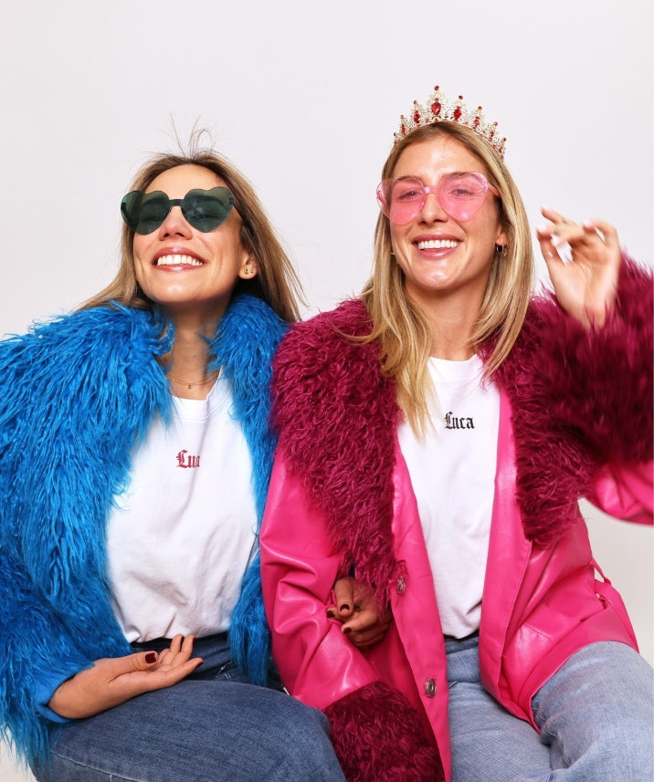 Joyful-photo-booth-style-image-of-two-friends-wearing-novelty- sunglasses-bright-coats-and- branded-Luca-t-shirts
