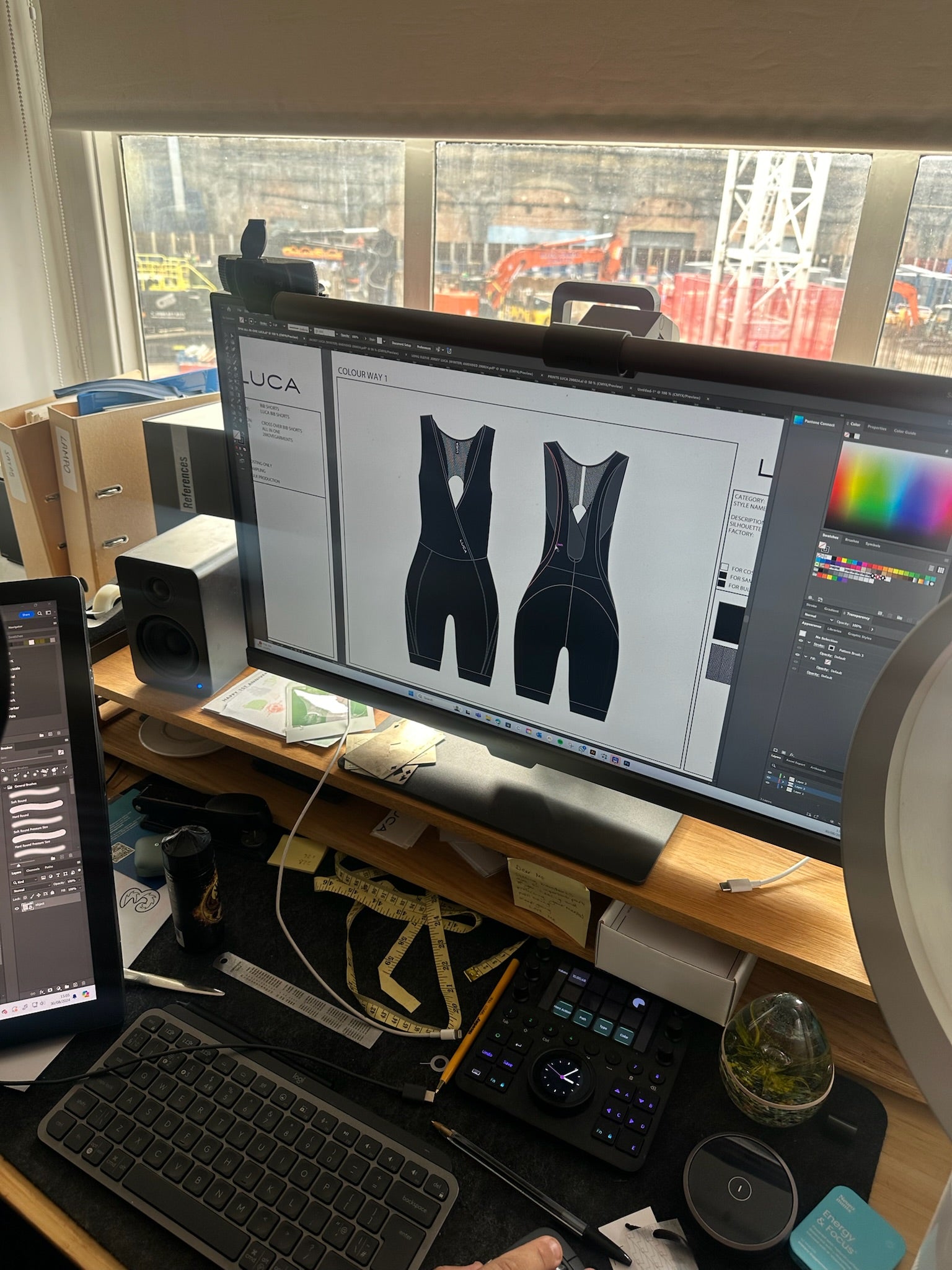 Desktop-view-showing-a-computer- screen-with-a-technical-drawing-of- black-cycling-bib-shorts-next-to-a- keyboard-and-design-tools