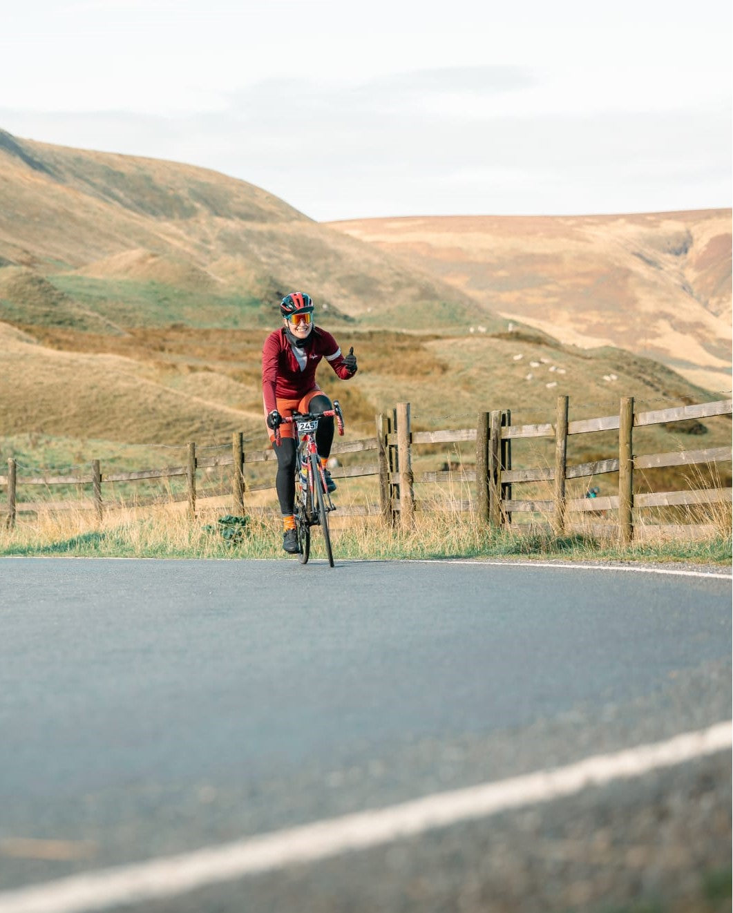 Full-length-view-of-a-female-cyclist- standing-outdoors-wearing-a-black- athletic-crop-top-and-black-cycling- leggings-with-a-bold-white-vertical- stripe-on-the-leg
