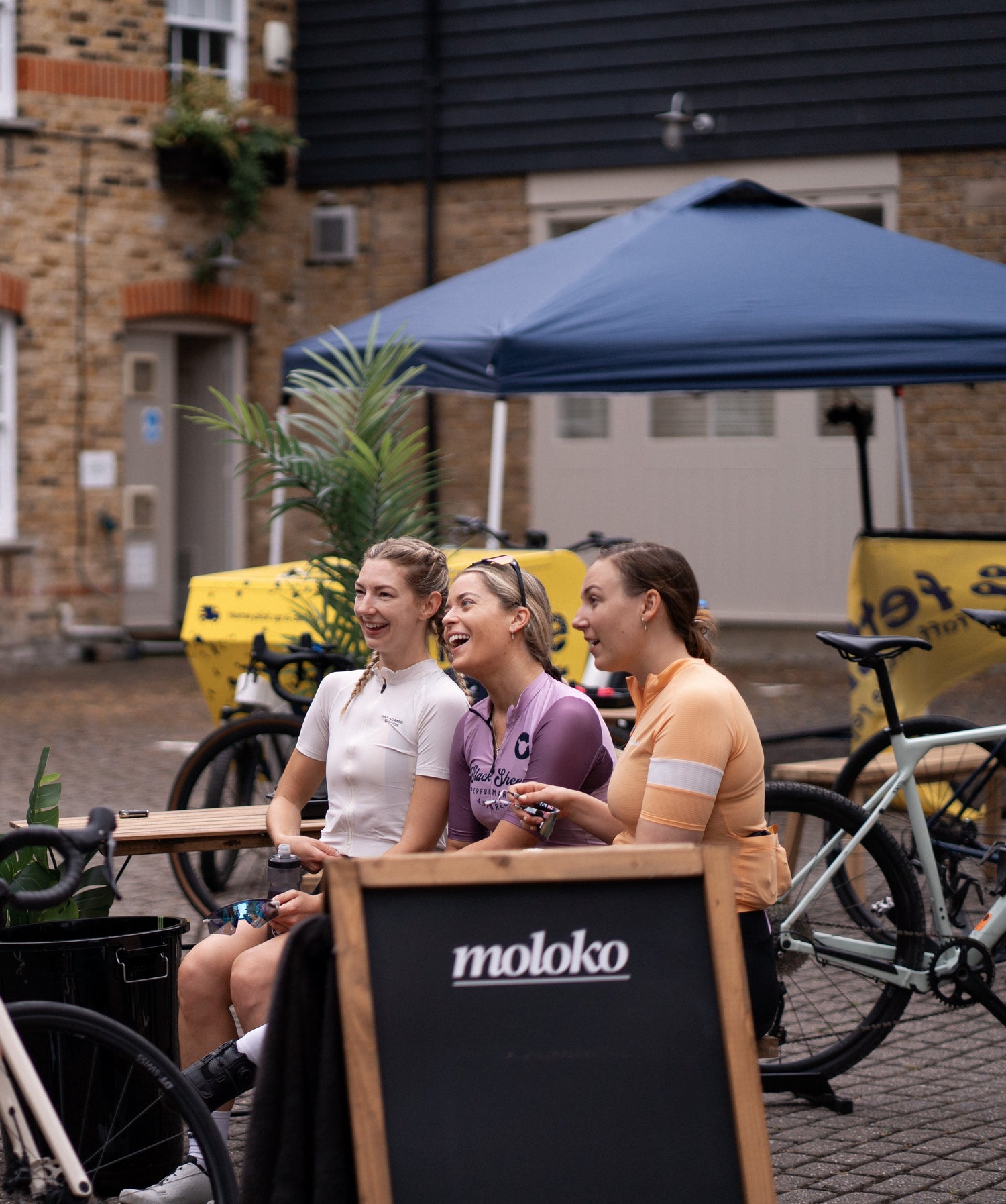 Female-cyclist-posing-with-a-bike- outdoors-wearing-a-black-zip-front- athletic-crop-top-and-white-cycling- shorts-with-a-black-stripe-detail