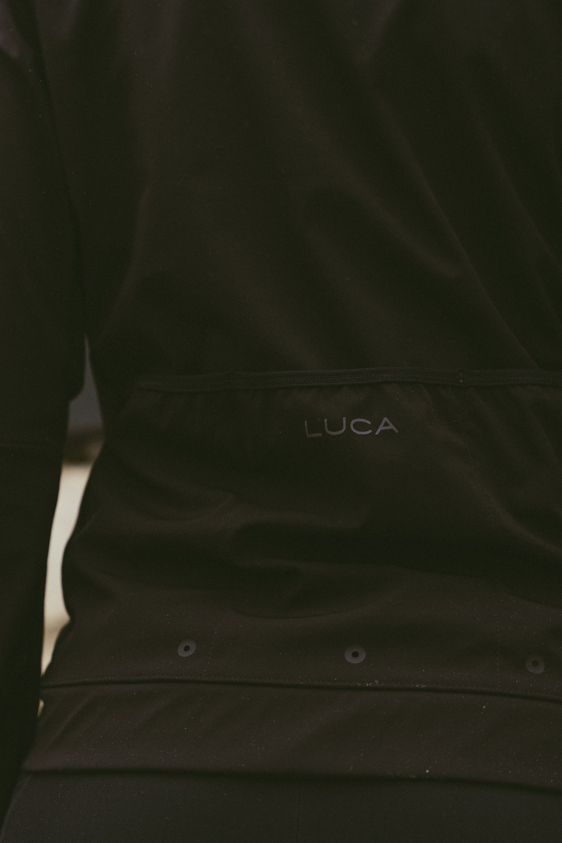 Back-detail-of-the-Luca-Momentum-Jacket-in-black-featuring-the-discrete-logo-and-horizontal-rear-pocket-design