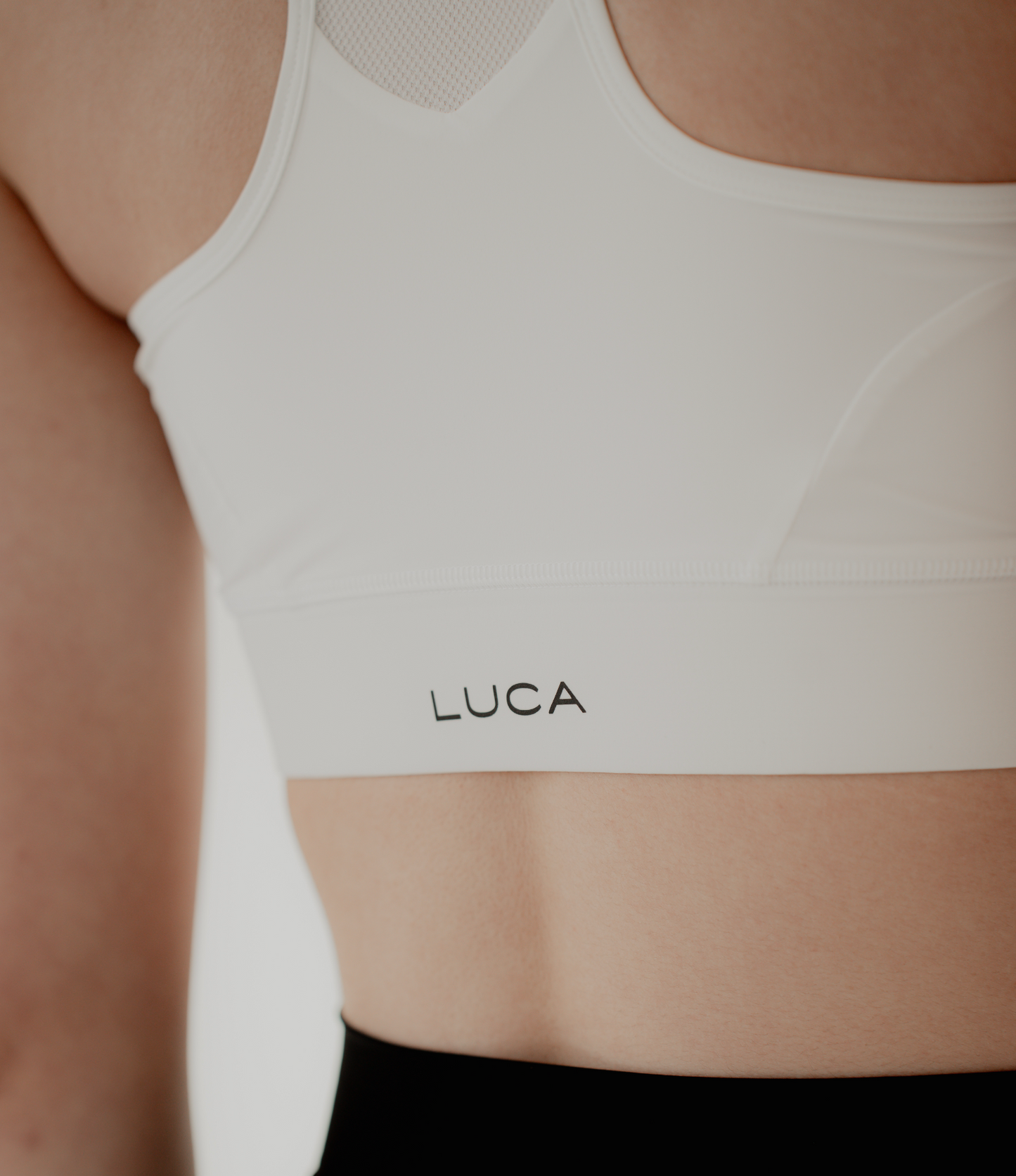 A-close-up-of-a-person-wearing-a-Sport-Bra-Off-White-with-the-brand-name-LUCA-printed-on-it