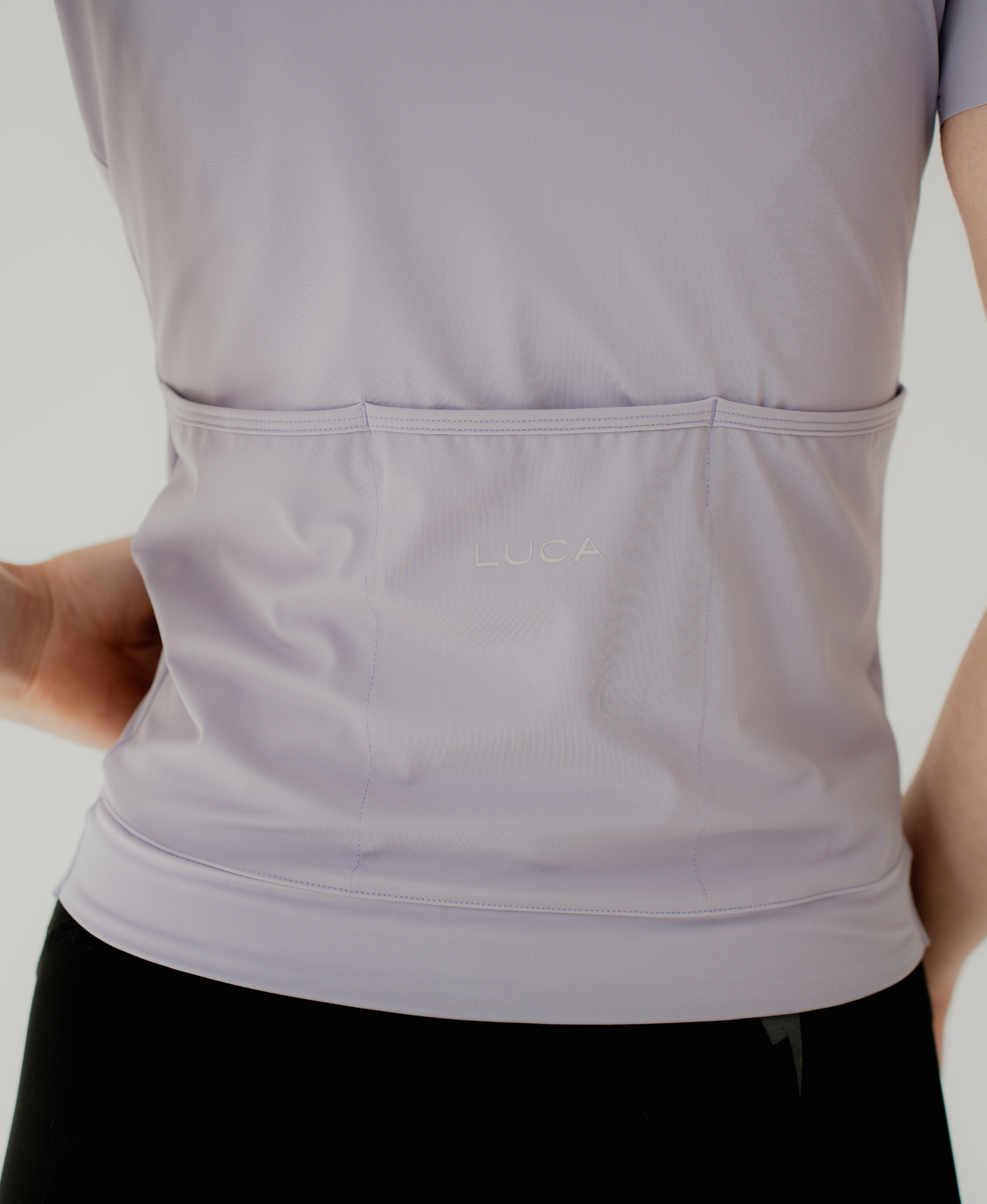 Close-up-back-view-of-the-lavender-cycling-jersey-clearly-showng-the-three-back-pockets-and-the-subtle-embroidered-LUCA-logo-centered-above-the-pockets