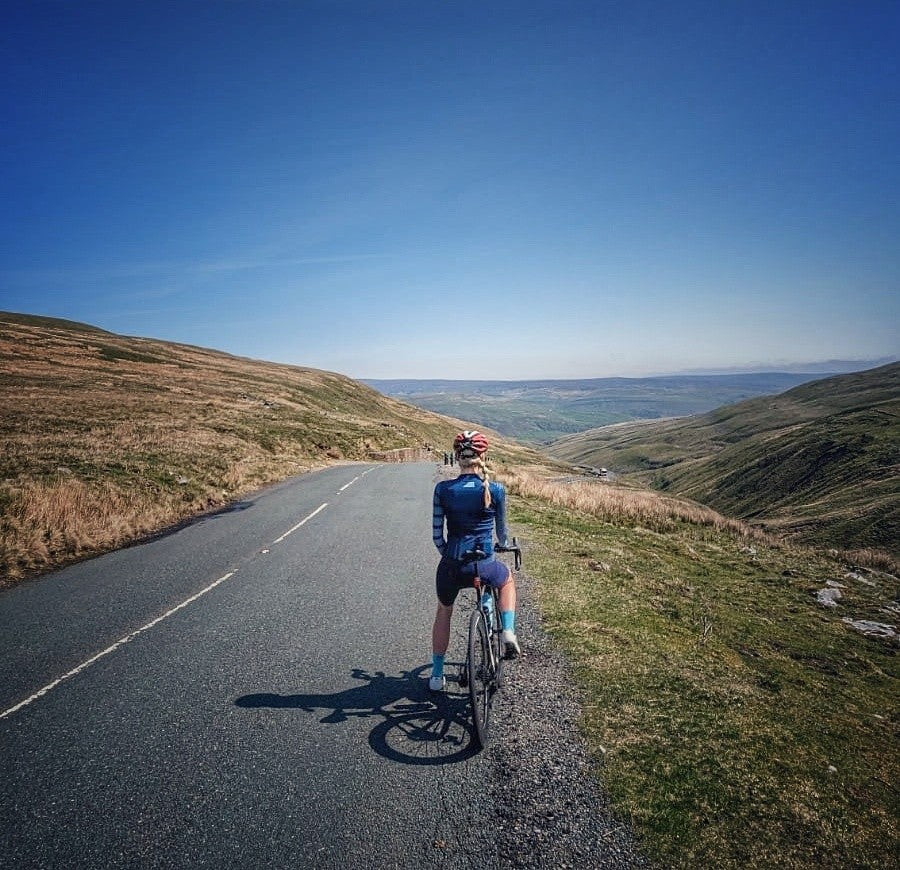 Solitary-cycling-on-an-epic-remote- road-with-stunning-valley-views- under-bright-sun