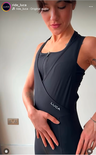 Torso-shot-of-a-model-showcasing- a-black-high-performance-athletic- garment-The-design-features-a- sleeveless-silhouette-a-wrap-style- V-neck-front-and-a-contrasting-inner-panel-with-a-small-quarter-zip-closure-The-white-LUCA- branding-is-printed-on-the-lower- torso