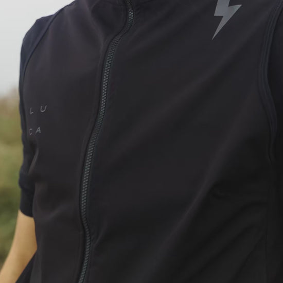 Short-video-clip-showing-a-model-wearing-the-Luca-black-cycling-vest-fully-zipped-The-west-features-a-lighting-bolt-graphic-on-the-shoulder-and-a-full-length-zipper-A-white-stripe-on-the-arm-of-the-underlying-short-sleeve-jersey-is-revealed