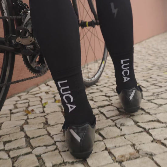 A-short-video-showcasing-a-person-wearing-black-Luca-mid-lenth-ccling-socks-The-clip-rotates-to-show-the-back-of-the-ankle-clearly-featuring-the-bold-vertical-white-LUCA-logo-and-the-socks-performance-knit-texture