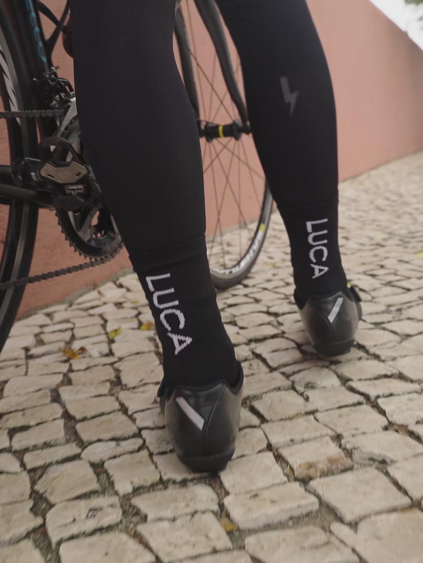 A-short-video-showcasing-a-person-wearing-black-Luca-mid-lenth-ccling-socks-The-clip-rotates-to-show-the-back-of-the-ankle-clearly-featuring-the-bold-vertical-white-LUCA-logo-and-the-socks-performance-knit-texture