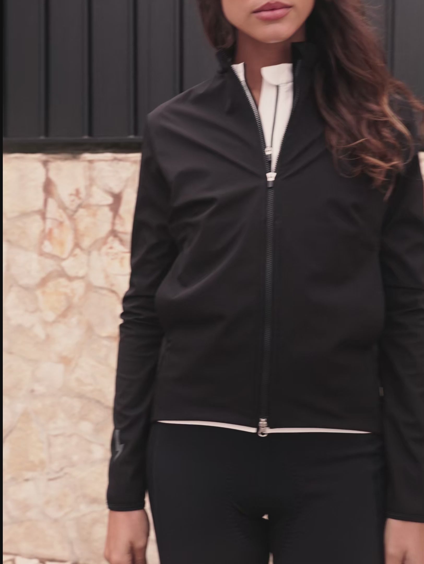 Video-thumbnail-showing-a-women-modeling-the-Black-Momentum-jacket-zipping-it-up-and-turning-to-reveal-the-reflective-lighting-bolt-sign-and-LUCA-branding-on-the-back-while-walking-outdoors