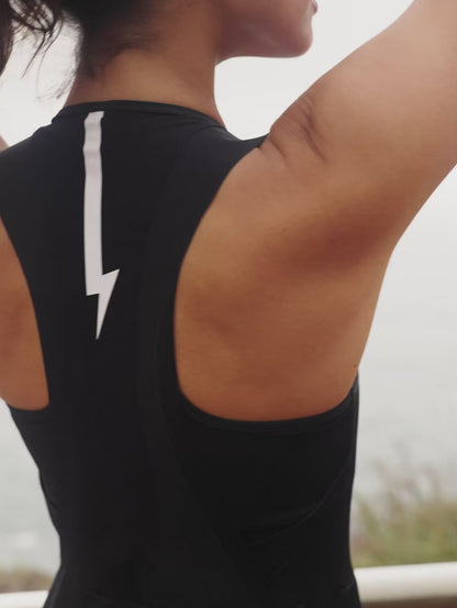 Short-video-demonstrating-the-fit-of-a-black-sleeveless-athletic-one-piece-  with-cycling-short-legs-a-square- neckline-and-a-contrasting-white- lightning-bolt-sign-on-the-upper-back