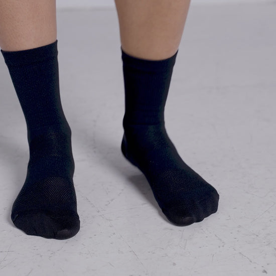 A-short-video-showcasing-a-person-wearing-black-mid-length-Luca-socks-The-video-rotates-around-the-feet-highlighting-the-subtle-mesh-knit-on-the-footbed-and-the-vertical-LUCA-logo-printed-in-white-on-the-back-of-the-calf