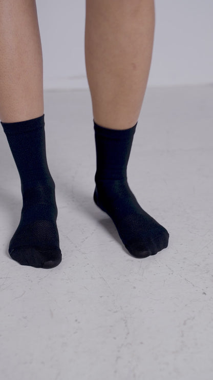 A-short-video-showcasing-a-person-wearing-black-mid-length-Luca-socks-The-video-rotates-around-the-feet-highlighting-the-subtle-mesh-knit-on-the-footbed-and-the-vertical-LUCA-logo-printed-in-white-on-the-back-of-the-calf