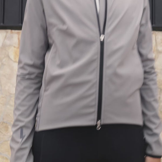 Short-video-clip-showcasing-the-Luca-grey-cycling-jacket-worn-by-a-women-The-clip-highlights-the-full-ziip-highlights-the-full-zip-closure-the-lighting-bolt-logo-on-the-sleeve-and-back-the-zipered-sde-pockets-and-the-rear-pockets-with-the-LUCA-branding-emphasizing-the-jacket-ergonomic-fit-and-features