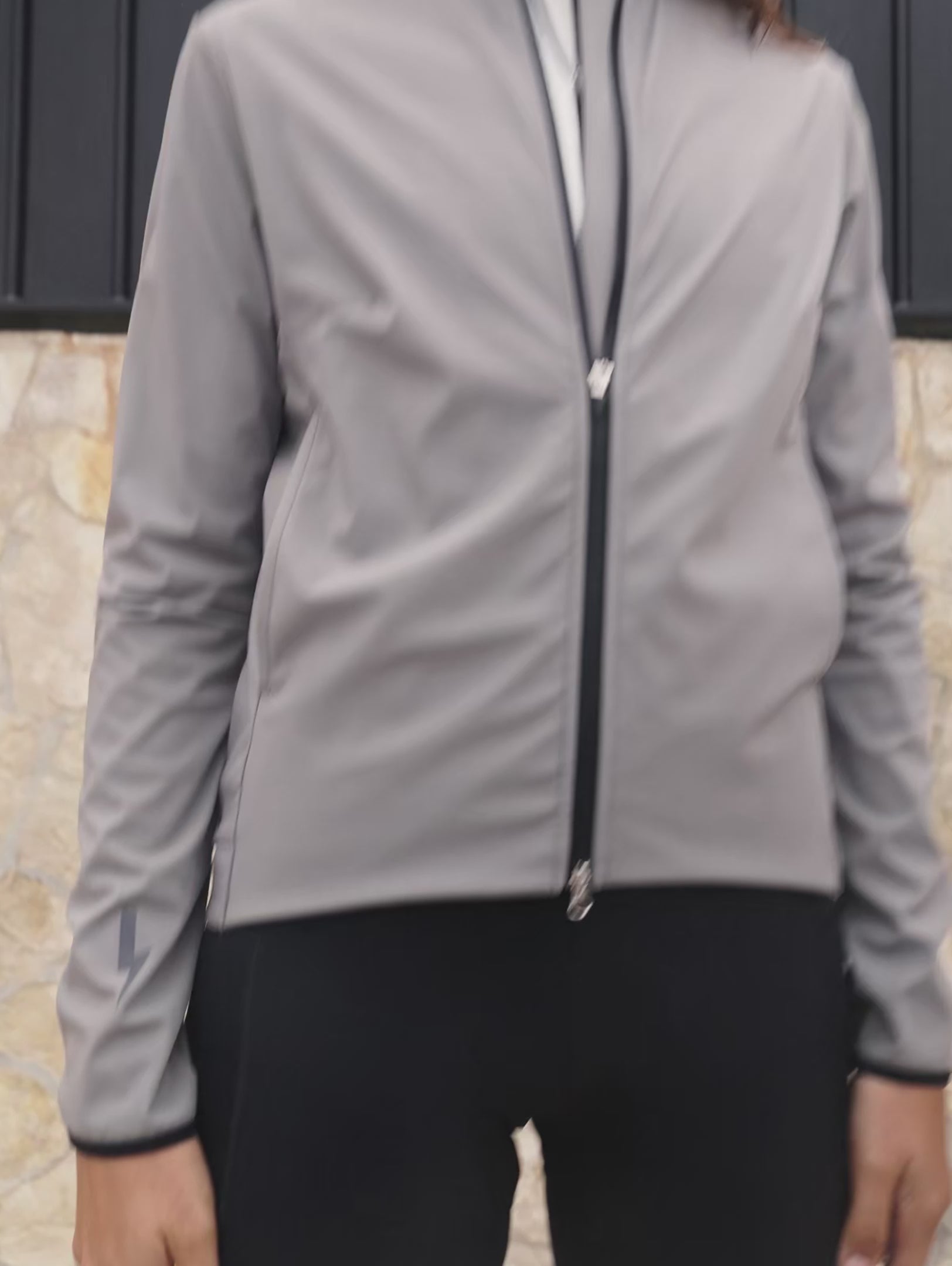 Short-video-clip-showcasing-the-Luca-grey-cycling-jacket-worn-by-a-women-The-clip-highlights-the-full-ziip-highlights-the-full-zip-closure-the-lighting-bolt-logo-on-the-sleeve-and-back-the-zipered-sde-pockets-and-the-rear-pockets-with-the-LUCA-branding-emphasizing-the-jacket-ergonomic-fit-and-features